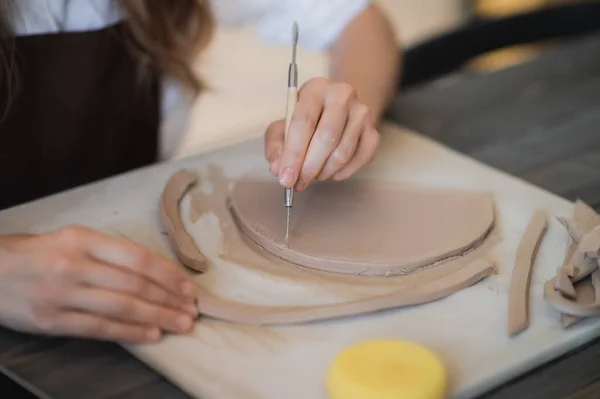 Doigts de femmes ajoutant et ajustant une partie en argile sur un futur produit céramique. — Photo