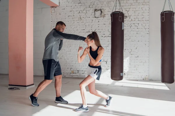 Il primo allenamento di una combattente alle prime armi nel kickboxing, l'allenatore mostra i colpi — Foto Stock
