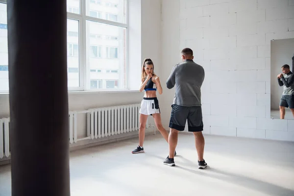 Un giovane allenatore di pugilato attraente prepara una bella ragazza per la competizione — Foto Stock