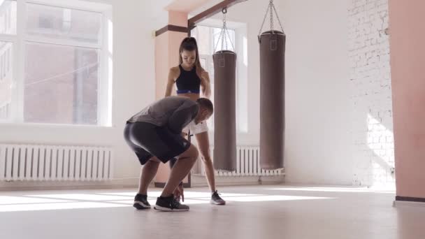 В боксерском зале опытный тренер учит молодую девушку правильной ноге. — стоковое видео