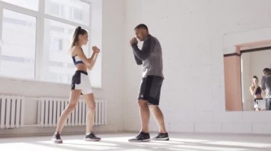 Tatlı kız kickboks tekniklerini spor salonunda tecrübeli bir antrenörle öğreniyor.