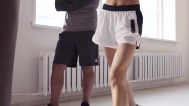 Boks stüdyosunda kişisel antrenörüyle vuruş talimi yapan kadın boksör..