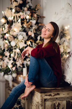 Noel hediyesi olan bir kadın klozete oturmuş Noel için dekore edilmiş. Arkadaki fidan ağacı