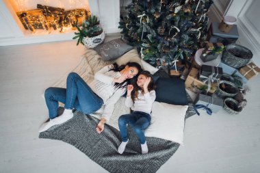 Mutlu anne ve kız Noel hediyelerini açıyor. Aile evdeki bir ağacın etrafında toplandı. Altında hediyeler olan Noel ağacı. dekore edilmiş oturma odası