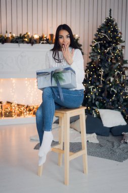 Noel kutusunu açarken heyecanlanan mutlu kız içinde ne olduğunu tahmin etmeye çalışıyor. Heyecanlı kadın. Noel Hediyesi