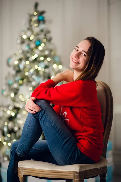 Porträtt av vacker kvinna med gåva sitter vid julgran hemma — Stockfoto