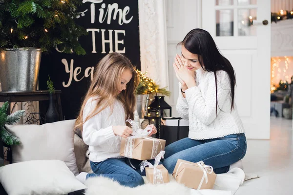 Joyeux Noël et Joyeuses Fêtes. Joyeux maman et sa fille mignonne fille ouvrant un cadeau de Noël. Parent et petit enfant s'amusent près de l'arbre de Noël à l'intérieur — Photo