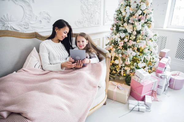 Mãe mostrando bebê algo no PC tablet perto da árvore de Natal — Fotografia de Stock