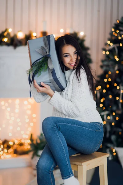 Щаслива дівчина в збудженні відкриває різдвяну коробку, намагаючись вгадати, що всередині. Захоплена жінка. Різдвяний подарунок — стокове фото