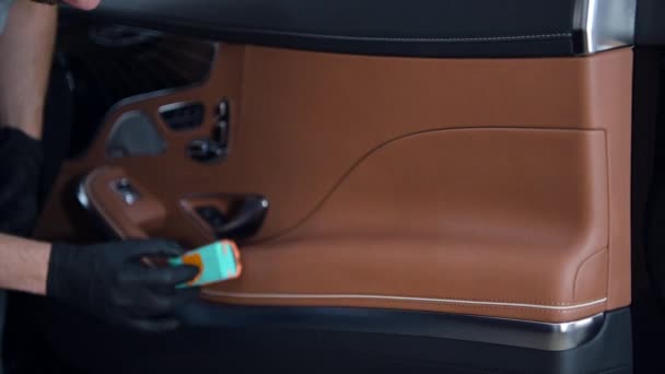 El hombre aplica recubrimiento de cerámica de vidrio líquido en la superficie de cuero de la puerta en el interior del coche de lujo. — Vídeos de Stock