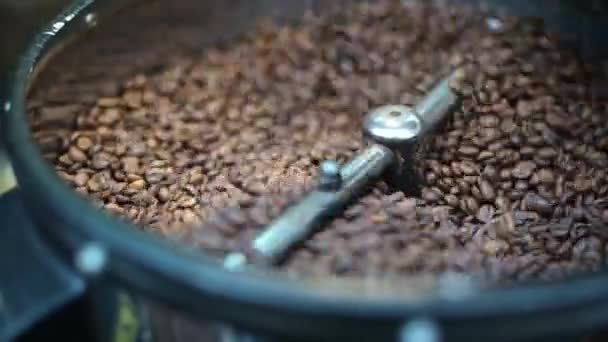 Processo de close-up de torrefação de grãos de café fritos frescos. Grãos de café processados são misturados em torno de uma placa de resfriamento do forno — Vídeo de Stock