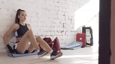 Kickboks eğitimine ara verildiğinde genç ve güzel bir kız duvarın yanında oturup su içiyor..