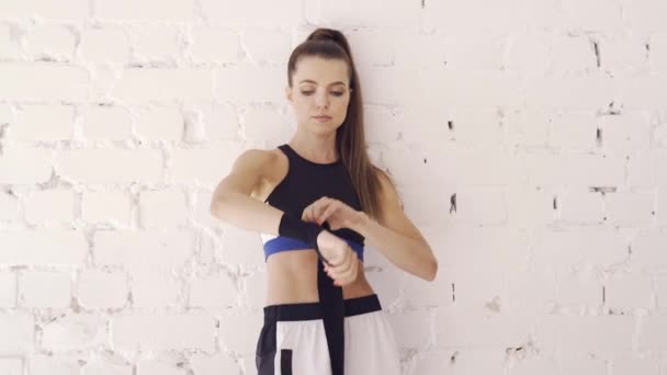 Una atleta bastante joven envuelve un vendaje de boxeo alrededor de su brazo antes de entrenar — Vídeos de Stock