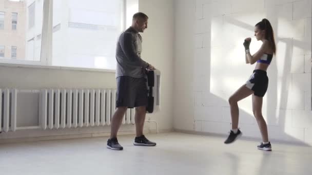 Kadın dövüş sanatları dövüşçüsü. Güneşli bir günde antrenörüyle bir boks stüdyosunda tekme antrenmanı yapıyor.. — Stok video