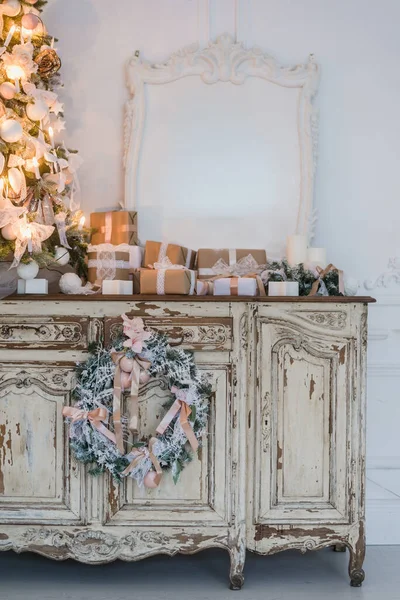 Árbol de Navidad en la cómoda cómoda de madera en el interior blanco, decorado con flores artificiales, guirnaldas y juguetes — Foto de Stock
