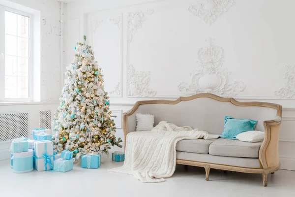 Stilvolles Weihnachtsinterieur mit elegantem Sofa. Wohnkomfort. Geschenke unterm Baum im Wohnzimmer — Stockfoto