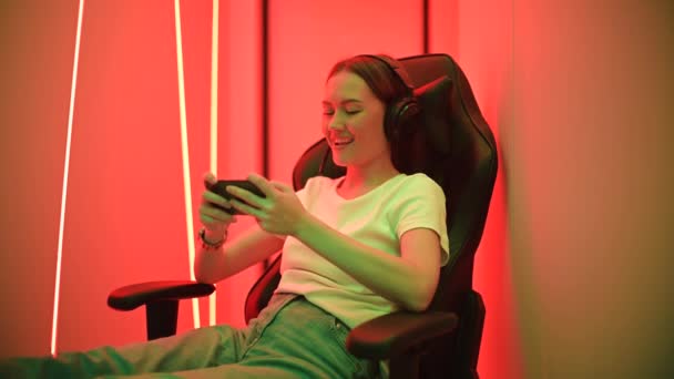 Ung kvinna spelar mobilspel glatt hemma — Stockvideo