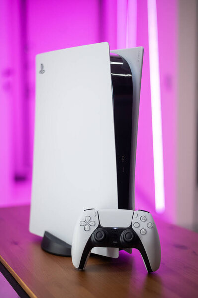 The new Sony gaming console PlayStation 5 and the DualSense controller in a pink neon color light. Moscow - November 28 2020.