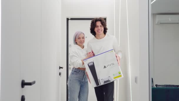 Happy young couple just came home from store with a brand new Sony PlayStation 5 gaming console. They got it on a Black Friday sale. Moscow - November 28 2020. — Stock Video