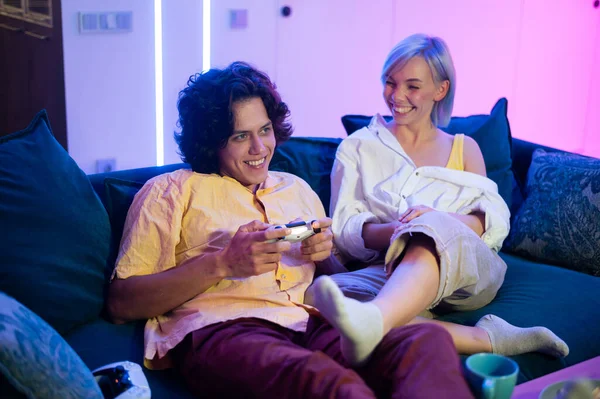 Молодые веселые кавказский муж и жена играют в видеоигры друг против друга дома наслаждаясь досугом замедленной съемки — стоковое фото