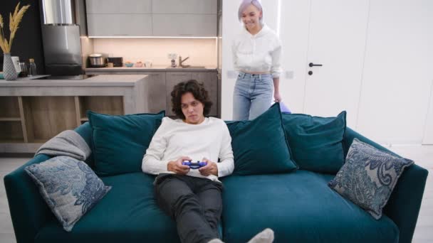 A fiatalember unatkozik, hogy a régi konzolján játsszon. A nő meglepetést okoz a barátjának egy vadonatúj Sony PlayStation 5 játékkonzollal otthon. Moszkva - november 28 2020. — Stock videók