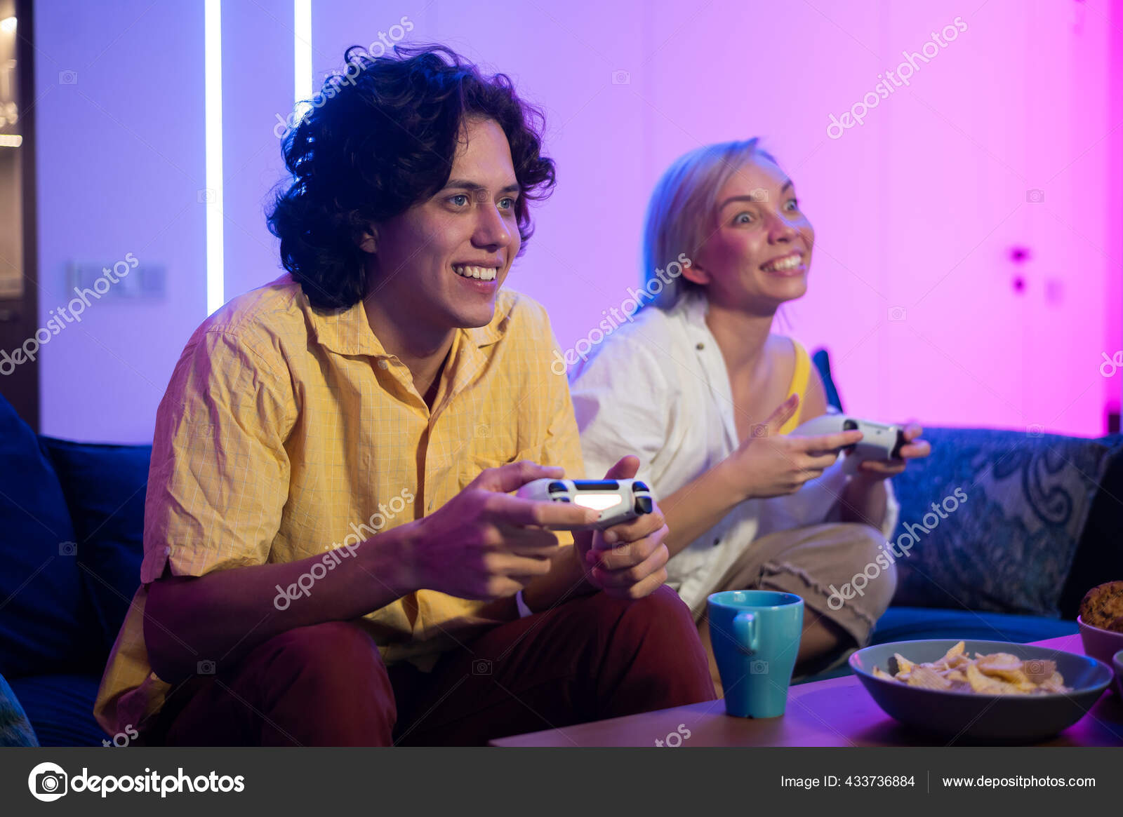 Happy boyfriend and girlfriend playing video games and holding