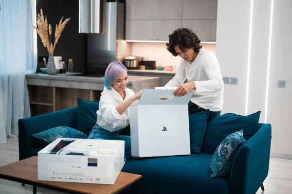 Heureux jeune couple déballer toute nouvelle console de jeu Sony Playstation 5 à la maison. Moscou - 28 novembre 2020. — Photo