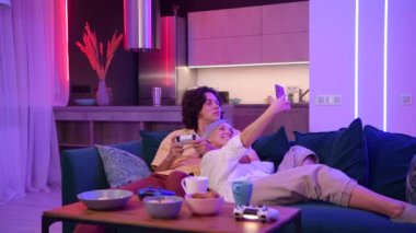 Cep telefonuyla internetten canlı yayın yapan bir kız evde kendini izole ederken sevgilisiyle nasıl vakit geçirdiğini. Oyun konsolunda video oyunu oynayan adam.