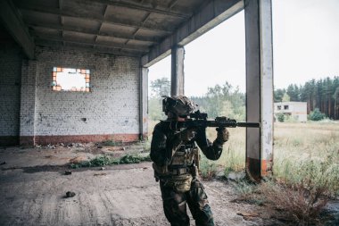 Tam teşekküllü Amerikan askeri MARSOC terk edilmiş binada saldırı tüfeğiyle koşuyor. Askeri çatışma..