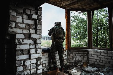 Silahlı bir asker, yıkılmış şehirde bir saldırı tüfeğini indiriyor. Askeri ve kurtarma operasyonu konsepti.
