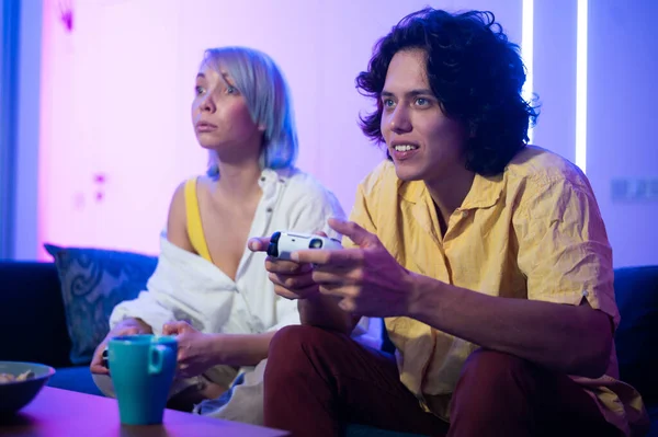 Lächelndes Paar mit Gamepads beim Videospiel zu Hause. Aufnahmen aus der Tiefkühltruhe von jungen Menschen, die während der Isolation gemeinsam Zeit mit einer Pandemie verbringen. — Stockfoto