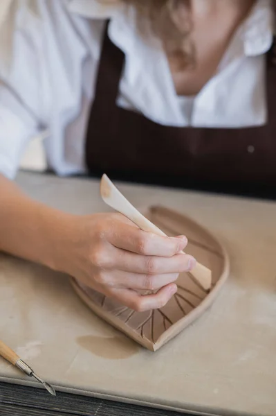 スティックを保持し、装飾品に飾りを作る女性の手。陶磁器工房の土師型粘土. — ストック写真