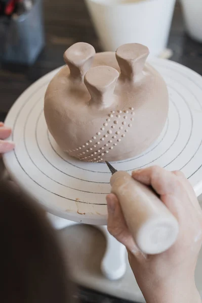 Main féminine tenant le bâton et faisant ornement sur le produit décoratif. Argile maître moulage argile sur un atelier de poterie et de céramique. — Photo