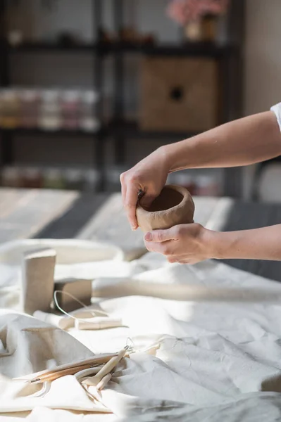 Una joven alfarera haciendo hierba en su propio lugar de trabajo. De pie en un amplio estudio creando la forma del futuro producto con sus manos. —  Fotos de Stock