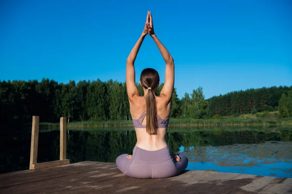 Beautiful young woman performing a spiritual yoga pose on a forest lake at sunny day, sunrise zen wellness — Stock Photo, Image