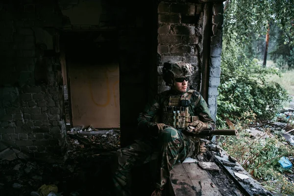 Brutal militar está sentado y limpiando y preparando su arma para la batalla. — Foto de Stock