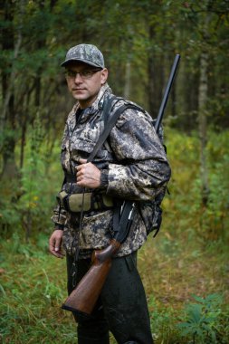 Avcı tüfekle dışarıda duruyor sonbahar ormanlarında kuş avına hazırlanıyor..