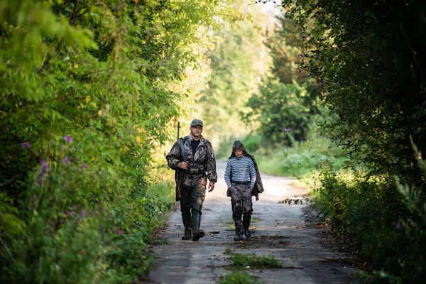 Apa és fia együtt sétálnak a szabadban puskával vadászatra. — Stock Fotó