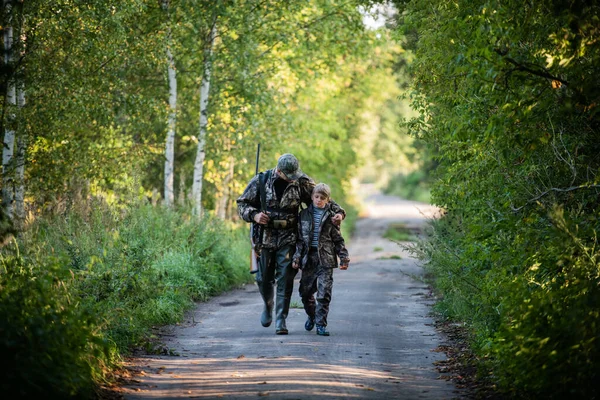 狩猎季节，带着狩猎装备的猎人在日出时分穿过农村森林. — 图库照片