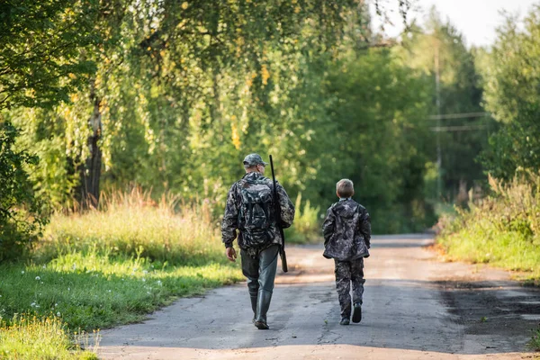 Apa és fia együtt sétálnak a szabadban puskával vadászatra. — Stock Fotó
