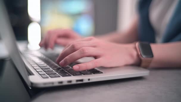 Крупный план женских рук с умными часами с помощью ноутбука, печатающего на клавиатуре в Интернете. Хорошие огни боке на заднем плане. — стоковое видео