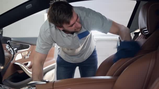 Un homme nettoie l'intérieur d'une voiture chère. Nettoyage des pièces intérieures automobiles avec une microfibre de la saleté. — Video