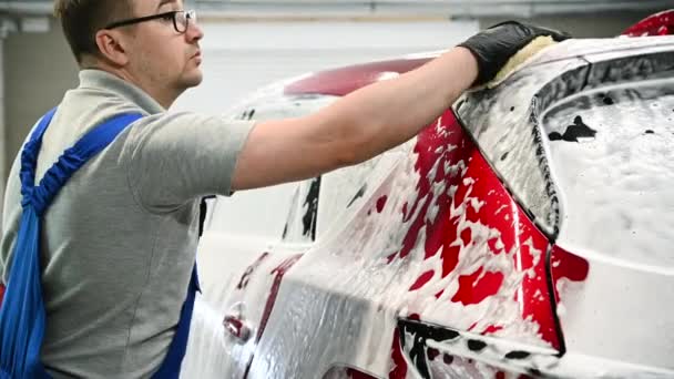 Hombre lavando un coche usando guantes de mano limpiando espuma. Primer plano de un proceso de limpieza automotriz. — Vídeos de Stock