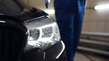 Araba yıkama servisi, elektrikli süpürge kullanarak araba temizleme. Su damlaları ağır çekimde yüzer..