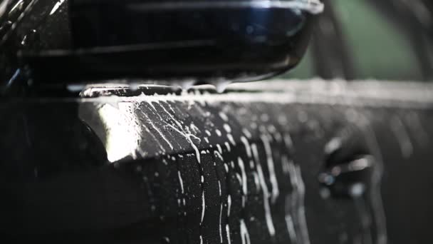 Cámara lenta primer plano del espejo del coche en el lavado de coches. Gotas de espuma goteando de un espejo lateral de un coche. — Vídeos de Stock