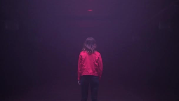 Achteraanzicht van een vrouw die in een donkere tunnel staat met lichteffecten. Abstracte horrorbeelden van een vrouw die alleen in het donker verblijft. — Stockvideo