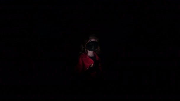 Karanlık bir koridorda ışık efektleriyle yalnız bir kadın bekliyor. Terk edilmiş binada kaybolmuş bir kadın cep telefonuyla yardım istemeye çalışıyor.. — Stok video