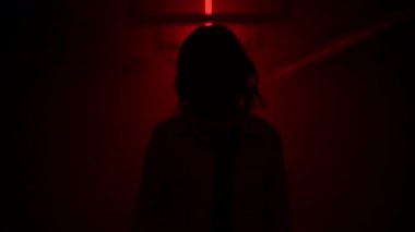Yüzü maskeli bir kadın, kırmızı ışıklarla karanlık bir tünelde duruyor. Pandemik depresyon kavramı. Koronavirüsün sebep olduğu depresyon, karantina, COVID 19. İnsan sağlığı.