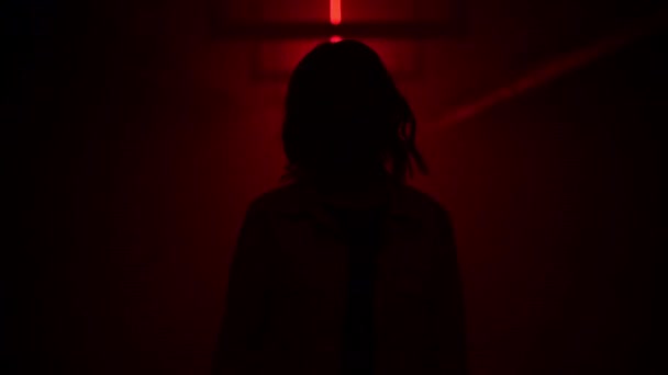 Kvinna i ansiktsmask som står i en mörk tunnel med rött ljus. Pandemisk depression. Depression orsakad av coronavirus, karantän, COVID 19. Människors hälsa. — Stockvideo