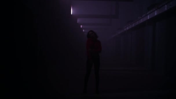 Woman dancing in a dark industrial hallway with light effects. Art motion effects. Background for music video. — Stock Video